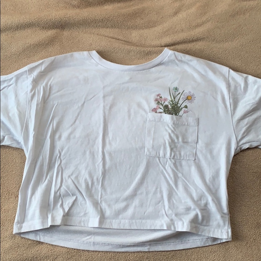 A white cropped t shirt with a pocket and flower.